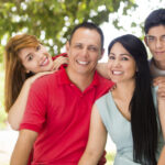 Latin family of four looking at camera and smiling