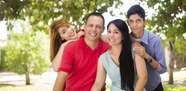 Latin family of four looking at camera and smiling