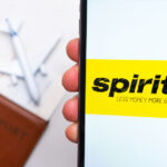 Spirit airlines logo on the screen of smartphone on the background of passport, ticket and plane, September 2021, San Francisco, USA